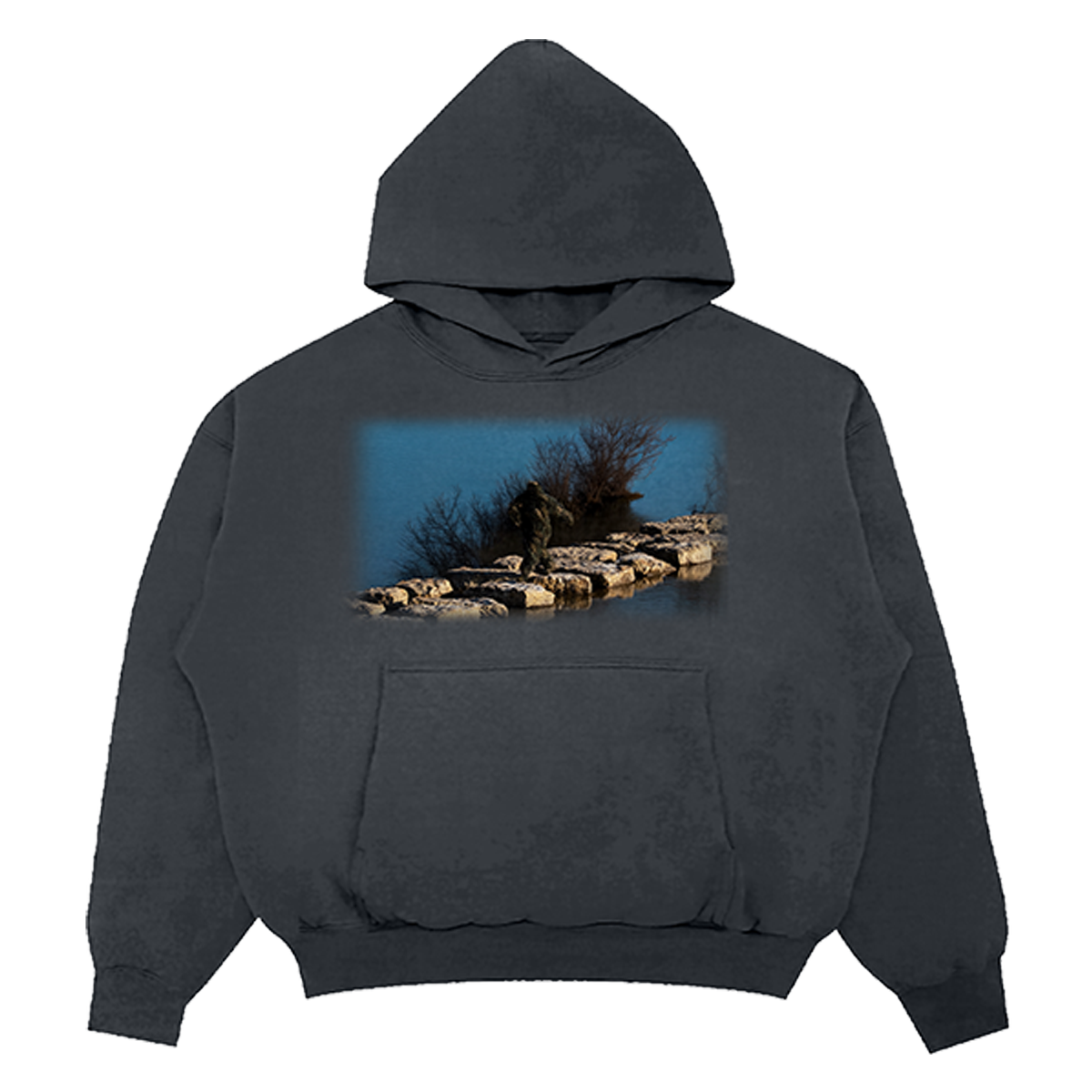 A dark charcoal gray pullover hoodie with a front kangaroo pocket and a rectangular graphic print on the chest depicting a person standing on rocks by a blue body of water.